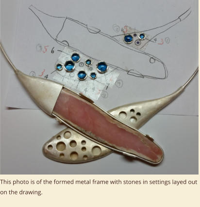 This photo is of the formed metal frame with stones in settings layed out on the drawing.